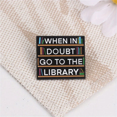 The "When In Doubt Go To The Library" Enamel Pin a large pin featuring a stylised bookshelf covered in books, and lettering proclaiming your love of all things library-related.
