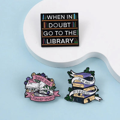 The "When In Doubt Go To The Library" Enamel Pin a large pin featuring a stylised bookshelf covered in books, and lettering proclaiming your love of all things library-related.