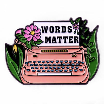 The "Words Matter" Enamel Pin features a stylised typewriter adorned with flowers and leaves, with "Words Matter" printed on the typewriter's paper. So true! They really do!