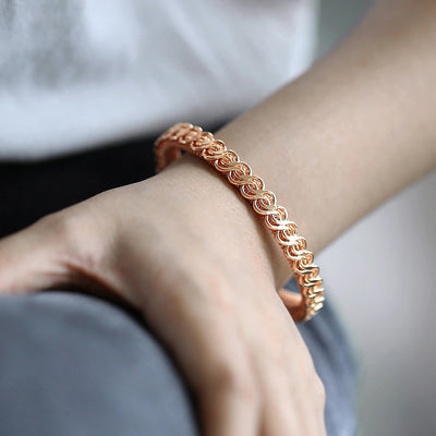 Hippolyta Stylized Woven Cuff Bangle - A sleek and elegant rose gold cuff bangle with a plaited, wave-like pattern on the outside and a fine mesh pattern on the inside.