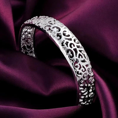 Jocasta Cut-Out Silver Cuff Bangle - An elegant yet chunky silver cuff with a floral/vine-like cut-out pattern, made from bright silver.