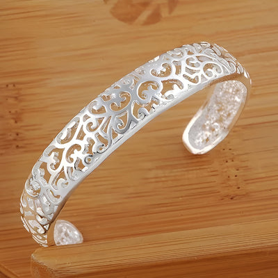 Jocasta Cut-Out Silver Cuff Bangle - An elegant yet chunky silver cuff with a floral/vine-like cut-out pattern, made from bright silver.