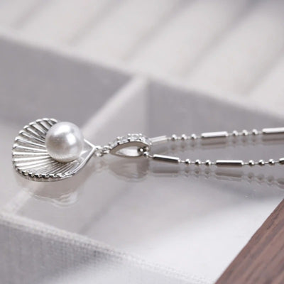 Kaimana Seashell Necklace - An elegant silver-coloured necklace featuring a seashell with a pearl at the end.