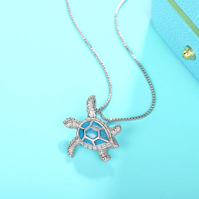Kealoha Iridescent Resin Turtle Necklace - A delicate silver coloured box chain with a small silver coloured pendant of a stylised turtle, with sparkly blue resin panels on its shell.