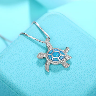 Kealoha Iridescent Resin Turtle Necklace - A delicate silver coloured box chain with a small silver coloured pendant of a stylised turtle, with sparkly blue resin panels on its shell.