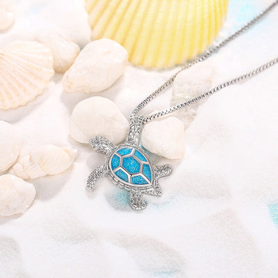 Kealoha Iridescent Resin Turtle Necklace - A delicate silver coloured box chain with a small silver coloured pendant of a stylised turtle, with sparkly blue resin panels on its shell.