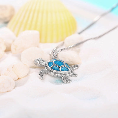 Kealoha Iridescent Resin Turtle Necklace - A delicate silver coloured box chain with a small silver coloured pendant of a stylised turtle, with sparkly blue resin panels on its shell.