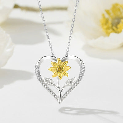 The Kelly Sunflower Heart Necklace - An elegant floral-themed necklace featuring a platinum plated heart with a beautiful yellow gold sunflower, and sparkling crystals.