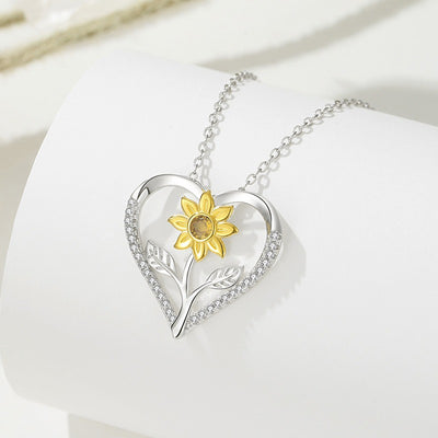 The Kelly Sunflower Heart Necklace - An elegant floral-themed necklace featuring a platinum plated heart with a beautiful yellow gold sunflower, and sparkling crystals.