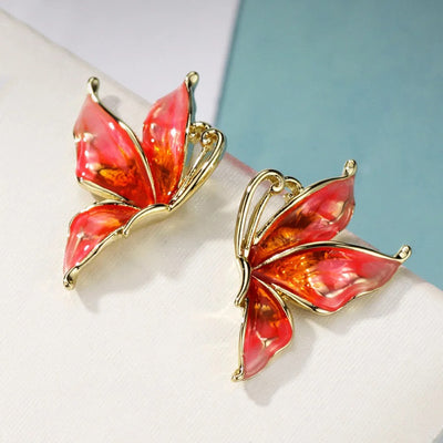 Lacquer Wings Enamel Earrings - Vibrantly colourful enamel earrings with a butterfly motif, available in blue, green, orange, and purple.