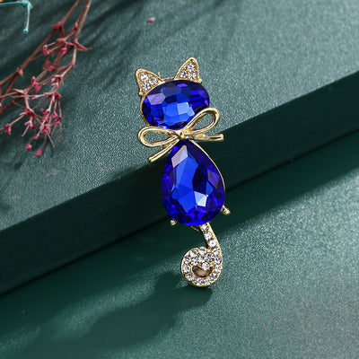 Mimmy Crystal Cat Brooch - A cute, stylised cat brooch featuring large coloured crystals for the head and body, and small round white quartz set into the ears and tail.