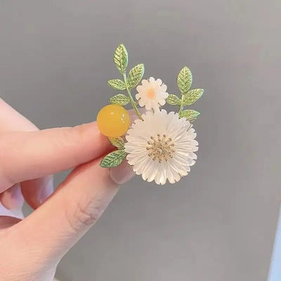 Nadine Daisy Enamel & Shell Brooch - A medium-sized, elegant floral brooch featuring two small stylised daisies, leaves, and a yellow ball.