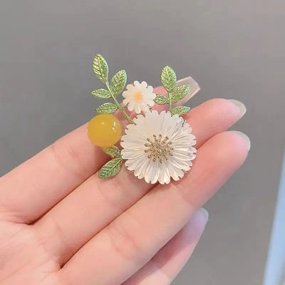 Nadine Daisy Enamel & Shell Brooch - A medium-sized, elegant floral brooch featuring two small stylised daisies, leaves, and a yellow ball.