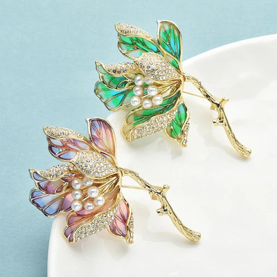 The Helena Hibiscus Sculpted Resin Brooch is a lovely, long, elegant piece that features seven ruffled petals clustered around a sprig of pearl stamen, with colourful resin to really make it pop and a dusting of crystal along the underside of the petals.