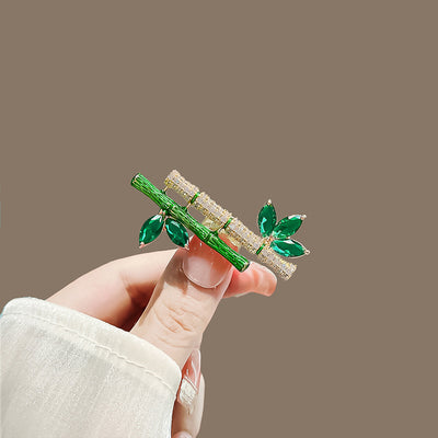 Sasae Crystal Bamboo Brooch - An elegant green brooch designed to look like a pair of stylised bamboo stalks, adorned with green and white crystals.