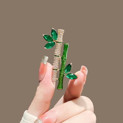 Sasae Crystal Bamboo Brooch - An elegant green brooch designed to look like a pair of stylised bamboo stalks, adorned with green and white crystals.