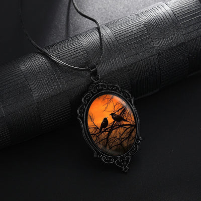 Sunset Ravens Cameo Necklace - A large gothic glass cabochon featuring an image of two silhouetted ravens or crows against a vibrant orange background.