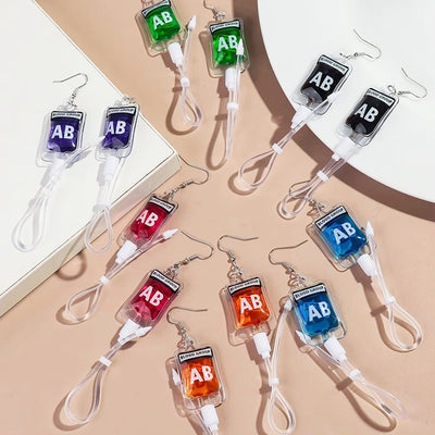 Teenytopia Alien Nurse Blood Bag - Cute, stylish Halloween earrings featuring a tiny bag of strangely-coloured blood and cables suspended from a French hook.
