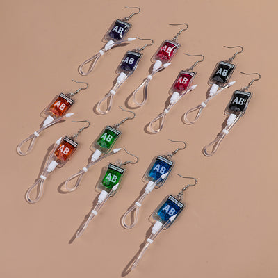 Teenytopia Alien Nurse Blood Bag - Cute, stylish Halloween earrings featuring a tiny bag of strangely-coloured blood and cables suspended from a French hook.