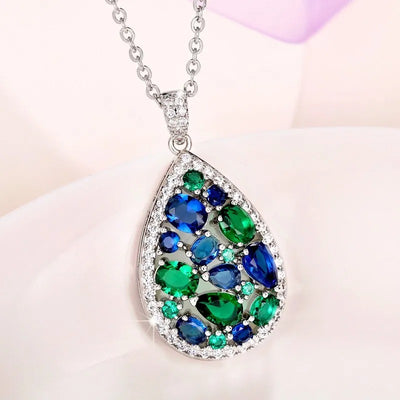 Terra Earth & Sky Crystal Drop Pendant & Earrings Set - An elegant teardrop-shaped pendant and earrings featuring a mixture of green and dark blue crystals, trimmed with delicate white crystals.