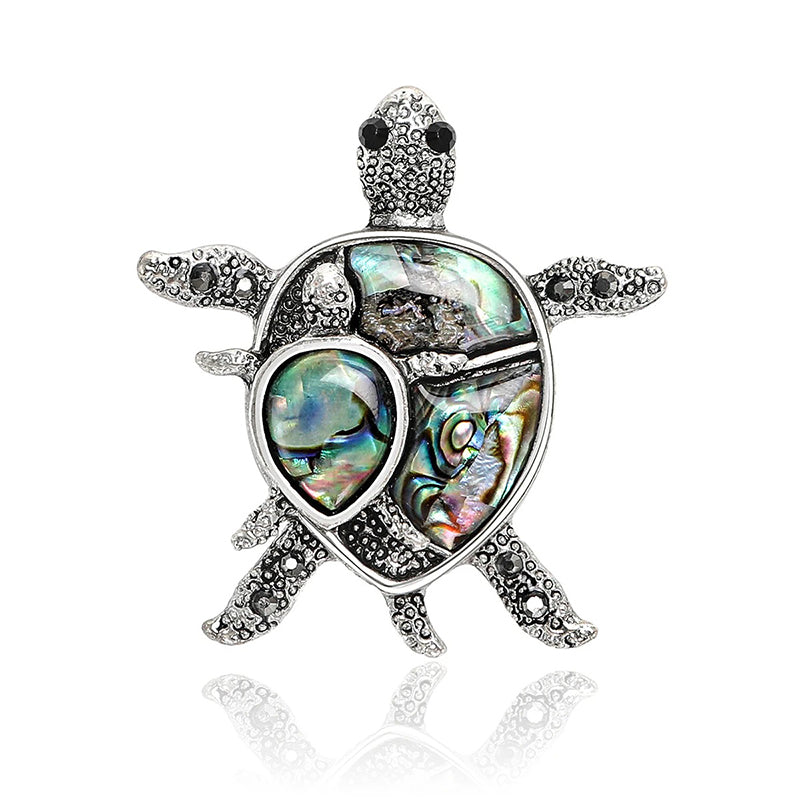 The Tropicana Honu Turtle Brooch - A beautiful silver-toned zinc alloy turtle brooch adorned with crystals and polished paua shell.
