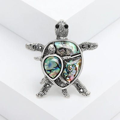 The Tropicana Honu Turtle Brooch - A beautiful silver-toned zinc alloy turtle brooch adorned with crystals and polished paua shell.