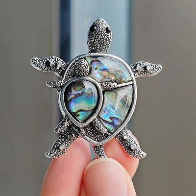 The Tropicana Honu Turtle Brooch - A beautiful silver-toned zinc alloy turtle brooch adorned with crystals and polished paua shell.