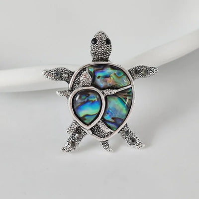 The Tropicana Honu Turtle Brooch - A beautiful silver-toned zinc alloy turtle brooch adorned with crystals and polished paua shell.