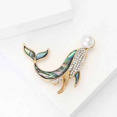 The Tropicana Kohola Whale Brooch - A beautiful gold-toned zinc alloy whale brooch adorned with polished paua shell and an artificial pearl.