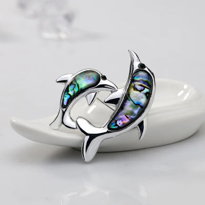 The Tropicana Nai'a Dolphin Brooch - A beautiful silver-toned zinc alloy dolphin brooch adorned with crystals and polished paua shell.