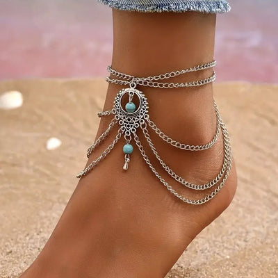 Delilah Bohemian Strand Anklet - A complex multi-strand dark silver anklet with lots of chains clustered around a central pendant, and a handful of turquoise beads.