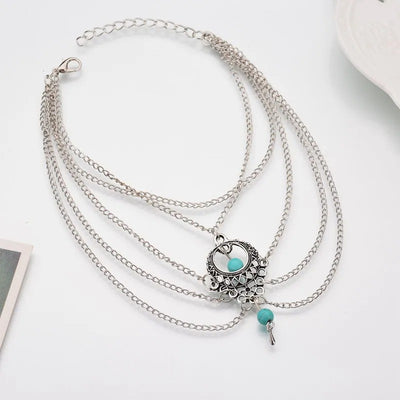 Delilah Bohemian Strand Anklet - A complex multi-strand dark silver anklet with lots of chains clustered around a central pendant, and a handful of turquoise beads.