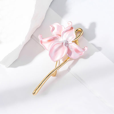 The Gwendolyn Lotus Enamel Brooch - A long, slender floral brooch featuring a stylized lotus blossom in subtle shades of pink and purple, and a golden stem.