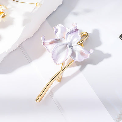 The Gwendolyn Lotus Enamel Brooch - A long, slender floral brooch featuring a stylized lotus blossom in subtle shades of pink and purple, and a golden stem.