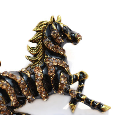 Zesty Zebra Brooch - A medium sized brooch shaped like a zebra running with its mane and tail flowing in the wind. It's available in gold or silver colours, and is studded with crystals.