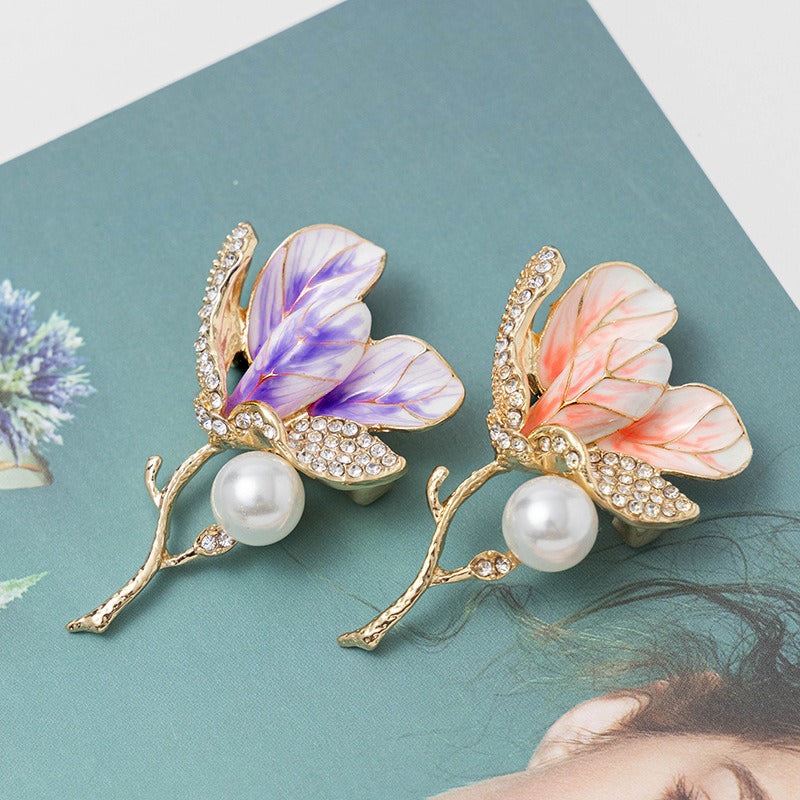 The Madeline Magnolia Blossom Brooch - A beautiful brooch featuring a sprig of petals, wrapped in sparkling crystals, attached to a slim, delicate stem.