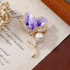 The Madeline Magnolia Blossom Brooch - A beautiful brooch featuring a sprig of petals, wrapped in sparkling crystals, attached to a slim, delicate stem.