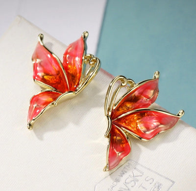 Vibrantly colourful enamel earrings with a butterfly motif, available in blue, green, purple, and red.