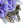 Zealous Zebra Brooch - A medium sized brooch shaped like a zebra standing still and looking forward, with a gold and black enamel background and studded with small crystals.