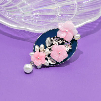 Ayana Cherry Blossom Brooch - An oval shaped blue brooch with silver coloured branches and pink flowers.