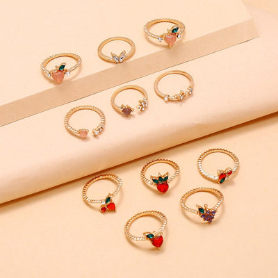 The Demeter Ring Set - Add some yummy sparkle to any outfit with the Demeter Ring Set! This set includes 11 adorable rings with a diverse fruit-and-flower theme and beautiful sparkling crystals across the board.