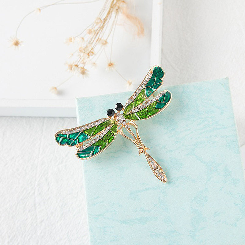 Estelle Dragonfly Brooch - A large green and gold dragonfly-themed brooch with metallic enamel paint on the wings and an assortment of shimmering crystals.