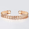 Hippolyta Stylized Woven Cuff Bangle - A sleek and elegant rose gold cuff bangle with a plaited, wave-like pattern on the outside and a fine mesh pattern on the inside.