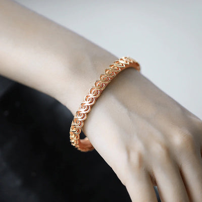 Hippolyta Stylized Woven Cuff Bangle - A sleek and elegant rose gold cuff bangle with a plaited, wave-like pattern on the outside and a fine mesh pattern on the inside.