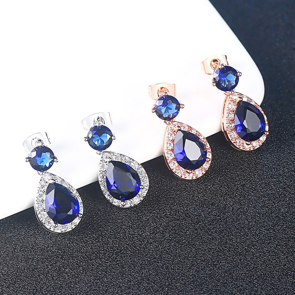 Imogen Luxury Crystal Dangle Earrings - Vintage-style earrings with a teardrop-shaped dark blue stone surrounded by little white stones, and a round stone on the lobe.