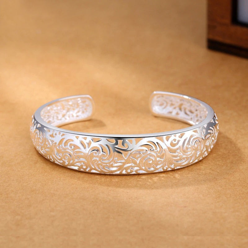 Jocasta Cut-Out Silver Cuff Bangle - An elegant yet chunky silver cuff with a floral/vine-like cut-out pattern, made from bright silver.