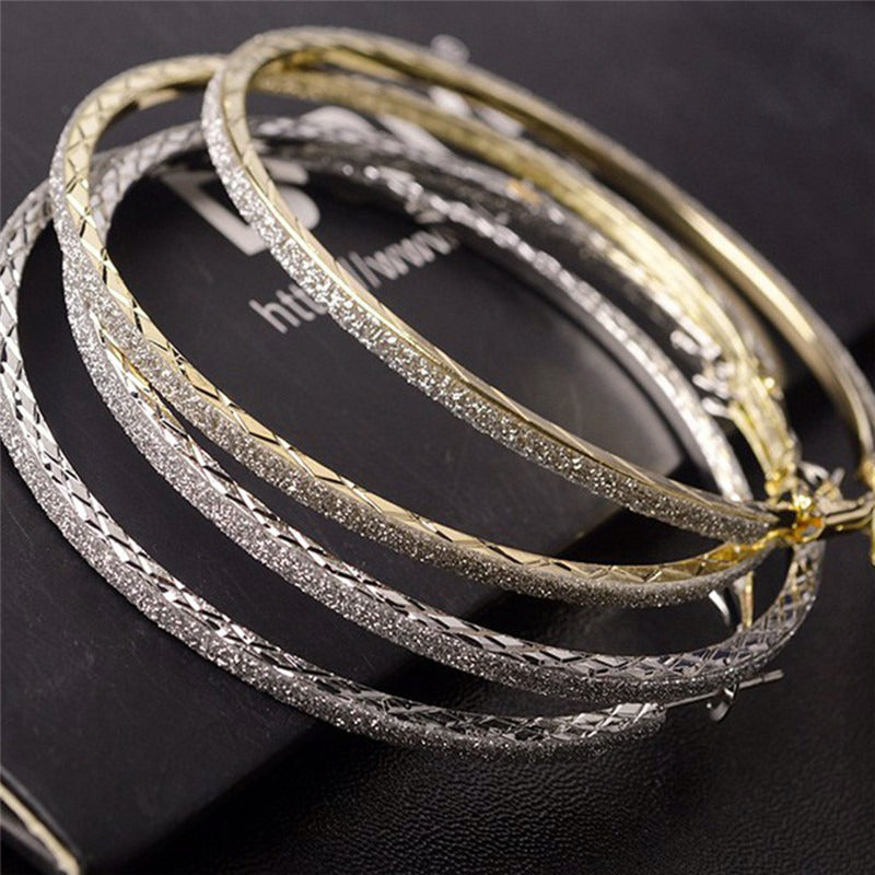 The Mariah Hoop Earrings - A pair of large 6cm hoop earrings encrusted with crushed rhinestone glitter, available in yellow gold or silver tone.