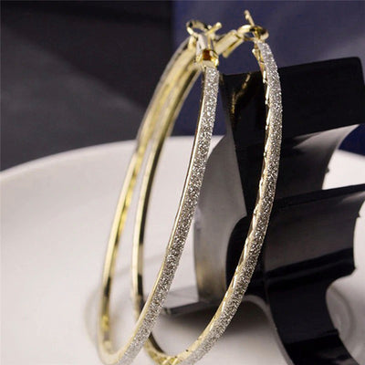 The Mariah Hoop Earrings - A pair of large 6cm hoop earrings encrusted with crushed rhinestone glitter, available in yellow gold or silver tone.