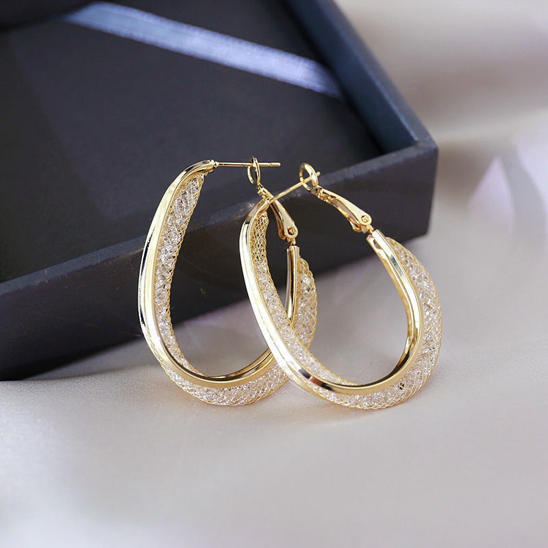 The Monique Crystal Mesh Oval Hoop Earrings - A pair of stunning crystal-filled mesh hoop earrings in an elegant asymmetrical oval shape. 
