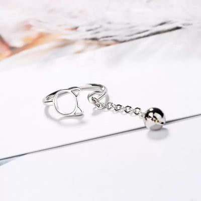 Tinklebell Silver Cat Bell Ring - An adjustable silver ring with a cat head charm on one side, and a small bell attached to a length of chain.